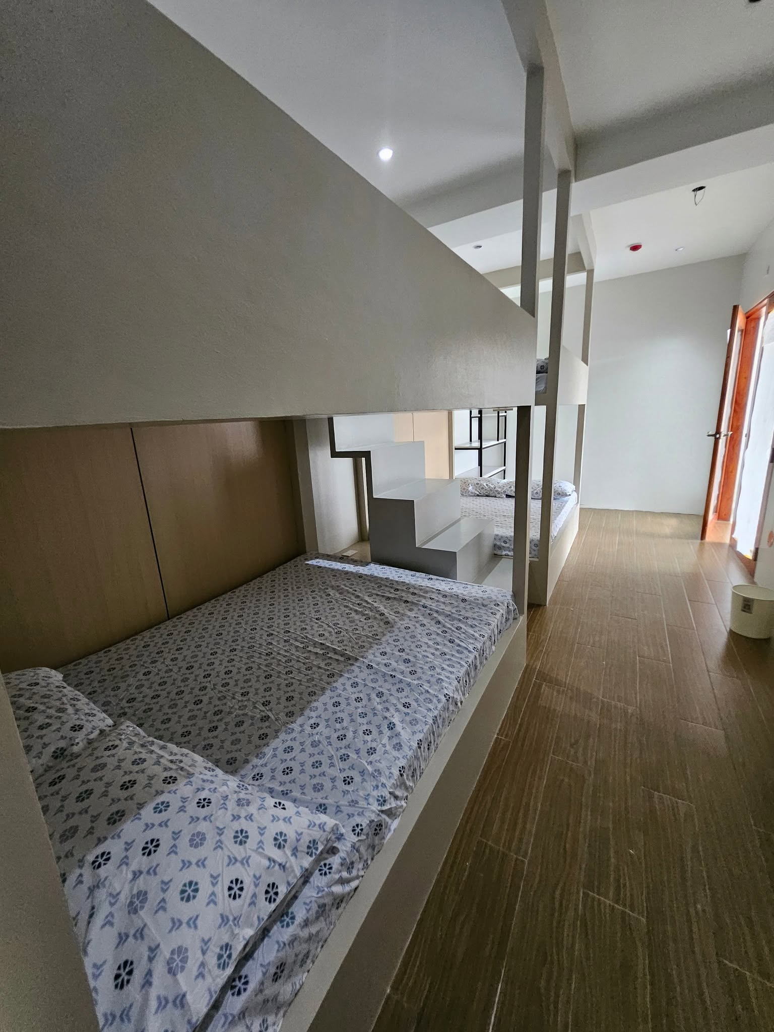 Built-in white bunk beds with patterned bedding, central steps and a tiled walkway.