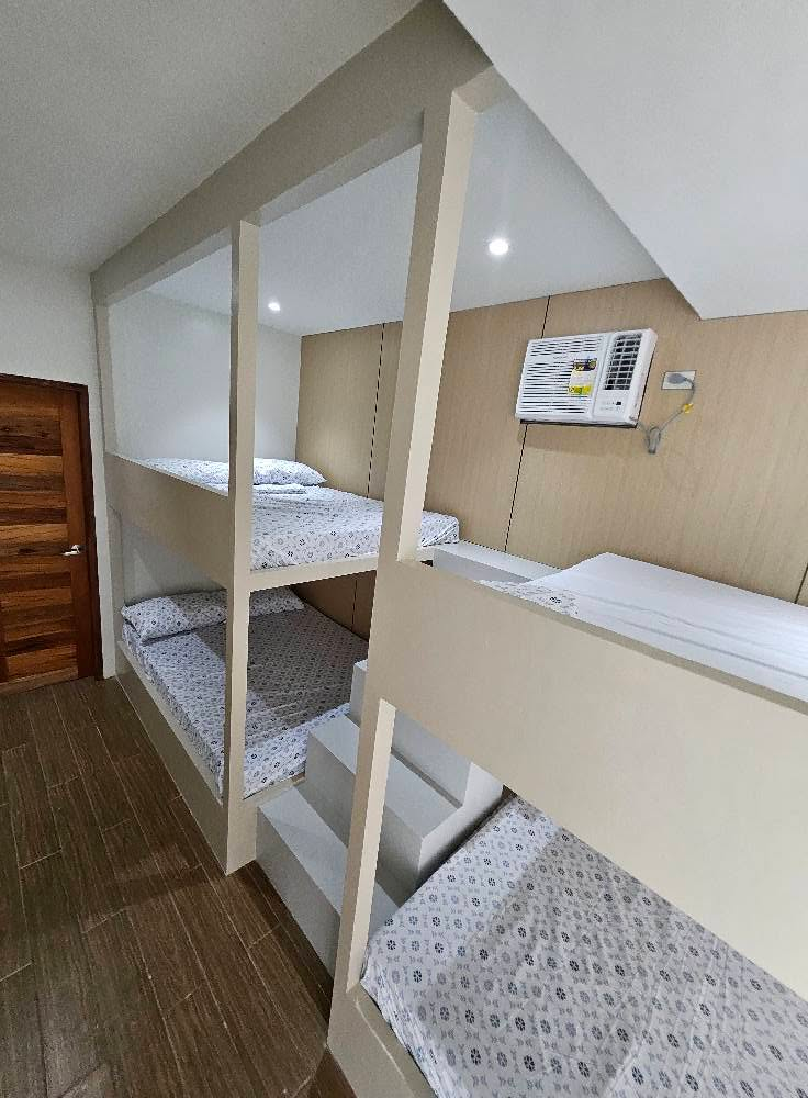 Built-in bunk beds with central steps beneath a wall-mounted air conditioner.