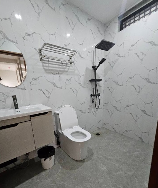 Tiled bathroom with a vanity, toilet, towel rack and black rainfall shower.
