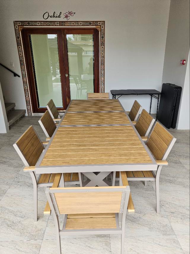 Wooden dining table and chairs beside the glass doors labeled Orchid.