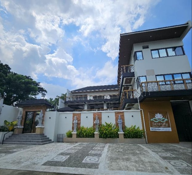 Street-facing view of Serenity with balconies, entrance steps, planting and property signage.