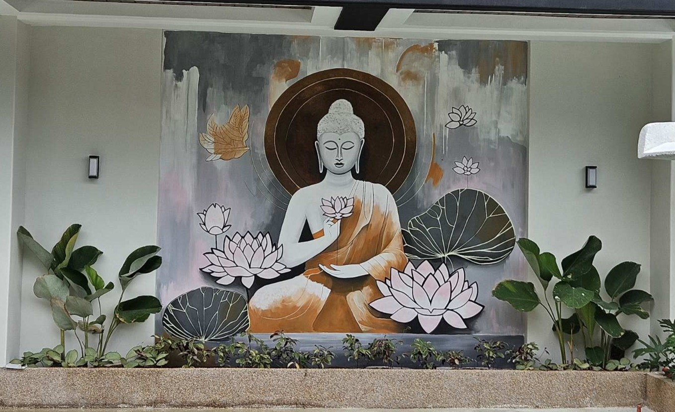 Large Buddha mural with lotus flowers above a planted courtyard border.