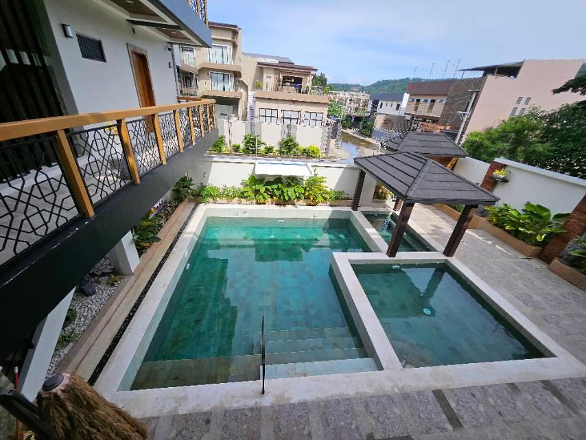 Elevated view of the main pool, adjoining smaller pools and roofed pavilion in daylight.