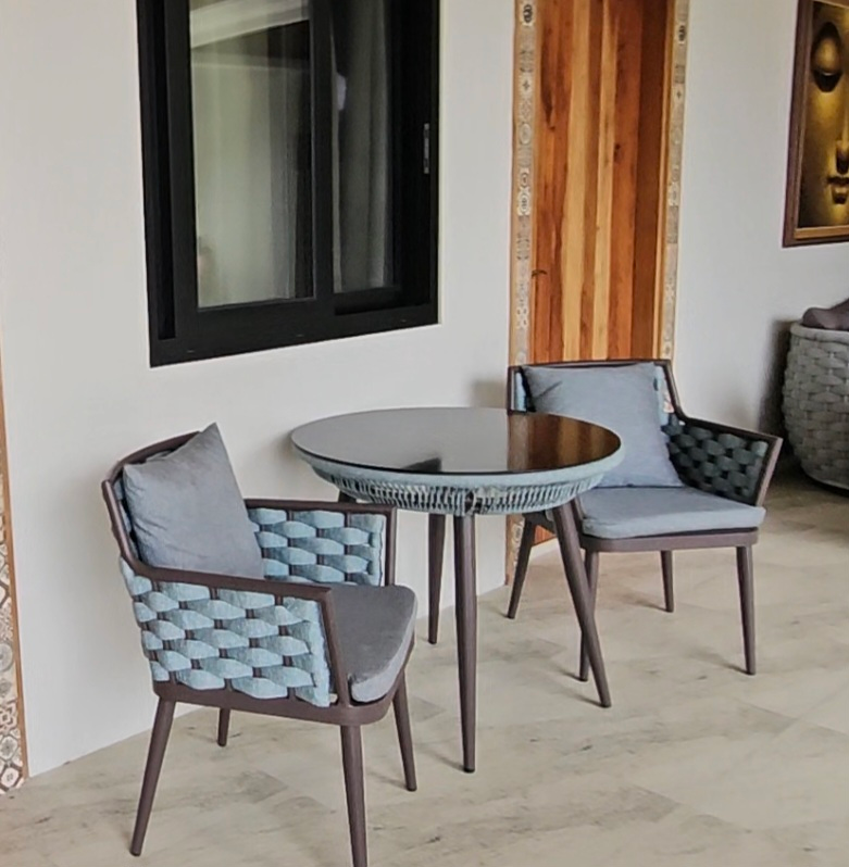 Two cushioned woven chairs beside a round table on the second-floor corridor.