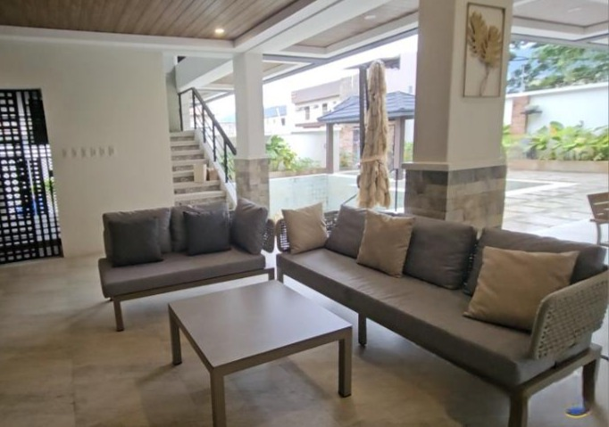 Cushioned sofas and a square coffee table in the covered lounge beside the pool.